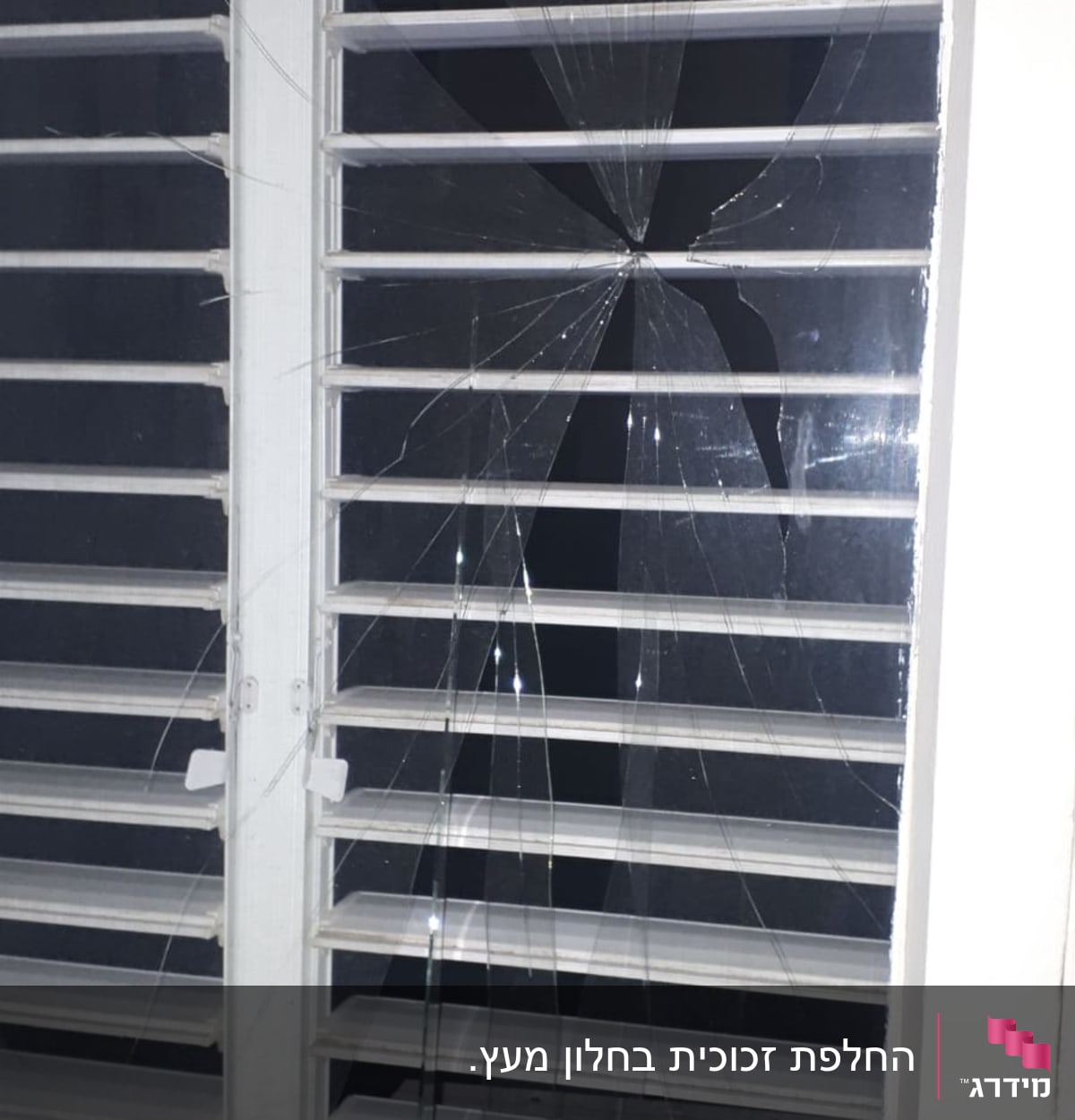 זכוכית שבורה בחלון עם תריסים לבנים